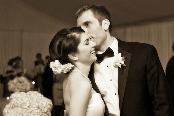 sepia photo - photo of the groom whispering into the laughing bride's ear at the reception -  photo by North Carolina based wedding photographers Cunningham Photo Artists